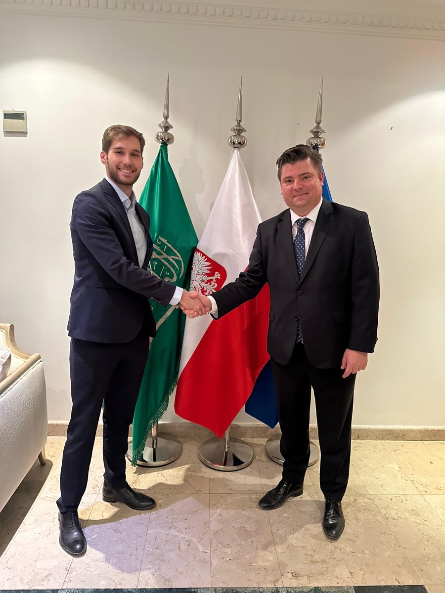 Handshake in front of Saudi Arabian and Polish flags at the Polish Embassy in Riyadh.